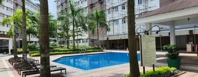 a swimming pool in front of a building with trees at Colin's Suite - Hope Residences, Trece Martires in Trece Martires