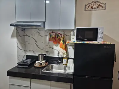 a small kitchen with a sink and a black refrigerator at Colin's Suite - Hope Residences, Trece Martires in Trece Martires