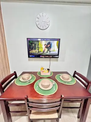 a dining room table with chairs and a clock on the wall at Shore Residence hosted by Nara Homes in Manila