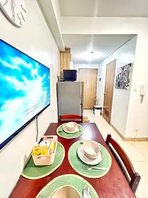 a dining room with a table and a tv at Shore Residence hosted by Nara Homes in Manila