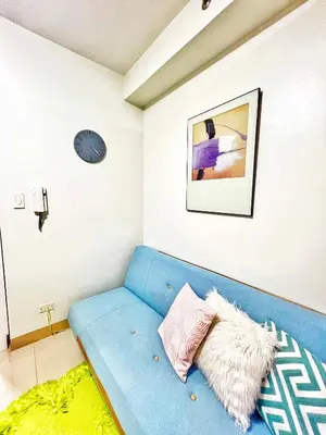 a blue couch in a room with a clock on the wall at Shore Residence hosted by Nara Homes in Manila