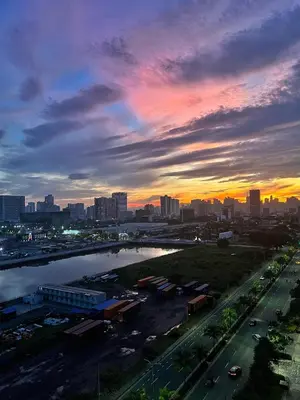 a sunset over a city with a river and a bridge at Shore Residence hosted by Nara Homes in Manila
