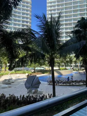 a view of a pool with a palm tree and buildings at Azure Daily by Trisha Sarmiento in Manila