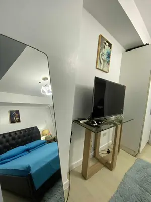 a mirror reflecting a bedroom with a bed and a tv at Azure Daily by Trisha Sarmiento in Manila