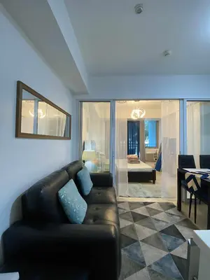 a living room with a leather couch and a dining room at Azure Daily by Trisha Sarmiento in Manila