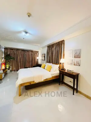a bedroom with a large bed and a table at Alex Staycation Home in BGC in Manila