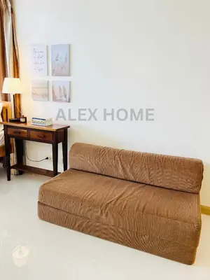 a brown couch in a living room with a table at Alex Staycation Home in BGC in Manila