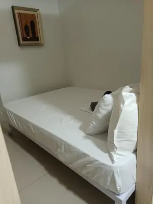 a bed with white sheets and pillows in a room at Sea Residences By Queen in Manila