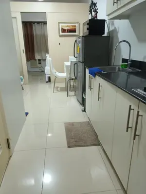 a kitchen with white tile floors and a sink and a counter at Sea Residences By Queen in Manila