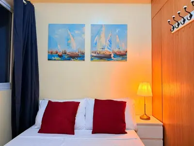 a bedroom with a bed with three paintings of sailboats at Cozy, budget-friendly stay for families and friends at Shell Residences by ONE Guest Place in Manila