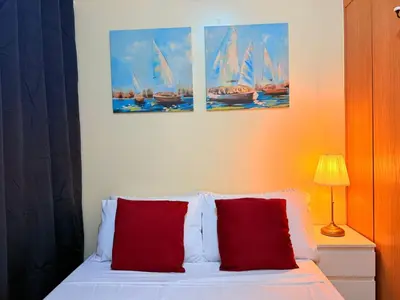 a bedroom with a bed with red pillows and three paintings at Cozy, budget-friendly stay for families and friends at Shell Residences by ONE Guest Place in Manila