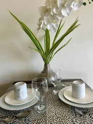 a table with plates and a vase with white flowers at The View Studio in Urban Deca Tower EDSA in Manila