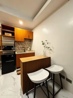 a kitchen with two white stools and a counter and a stove at Kai cabins SELF CHECK IN NEAR NAIA 1 & 2 in Manila