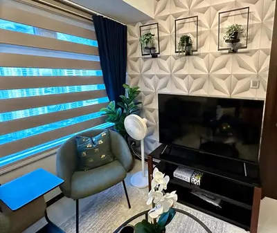 a living room with a chair and a television at Stay at Downtown Suite 2 in BGC, Taguig City in Manila
