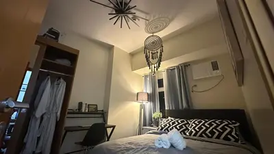 a bedroom with a bed and a chandelier at Classy BGC Condo City View Pool Gym Sauna in Manila