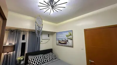 a room with a chandelier and a bedroom with a bed at Classy BGC Condo City View Pool Gym Sauna in Manila