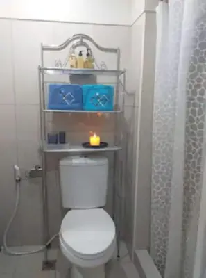 a bathroom with a toilet with a candle on a shelf at MOA Staycation - Shell Condo in Manila