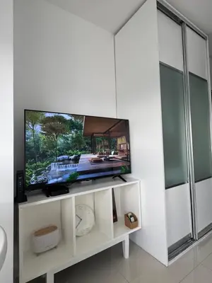 a flat screen tv sitting on top of a white entertainment center at La Casa Zen - Cozy Studio with private Wi-Fi, complimentary access to Fitness Centre, swimming pool and stunning city view located near the CBD of Ortigas, Makati, BGC in Manila