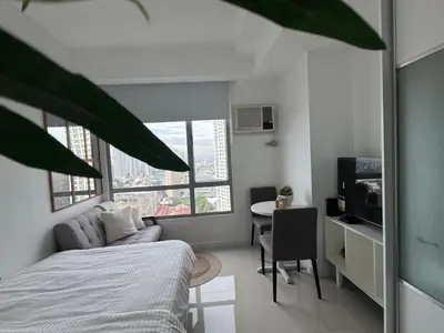 a bedroom with a bed and a desk and a table at La Casa Zen - Cozy Studio with private Wi-Fi, complimentary access to Fitness Centre, swimming pool and stunning city view located near the CBD of Ortigas, Makati, BGC in Manila