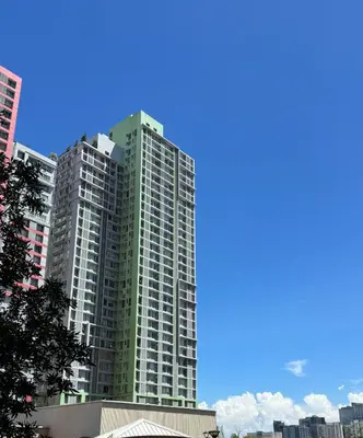 a tall green building in a city at La Casa Zen - Cozy Studio with private Wi-Fi, complimentary access to Fitness Centre, swimming pool and stunning city view located near the CBD of Ortigas, Makati, BGC in Manila