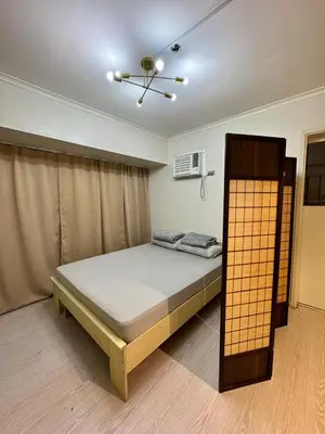 a bedroom with a bed and a ceiling fan at Cozy Spacious BGC Condo near SM Aura, High Street in Manila