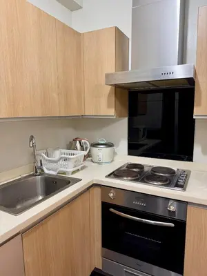 a kitchen with a sink and a stove top oven at Cozy Spacious BGC Condo near SM Aura, High Street in Manila