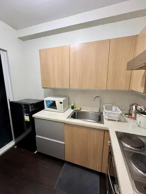 a small kitchen with a sink and a microwave at Cozy Spacious BGC Condo near SM Aura, High Street in Manila