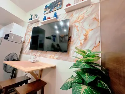 a room with a tv and a table and a plant at Makati Stay Ph in Manila