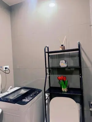 a bathroom with a toilet and a shelf with red tulips at Makati Stay Ph in Manila