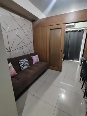 a living room with a brown couch with two pillows at Shell residences Near Moa Japs staycation in Manila