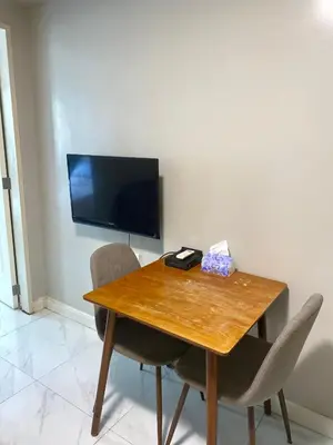 a wooden table with two chairs and a television on a wall at Monarch Parksuites in Manila
