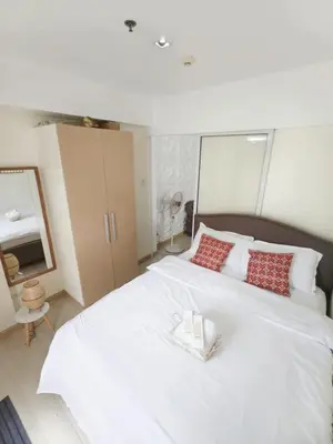 a bedroom with a large white bed with red pillows at Boracay by SIA in Manila