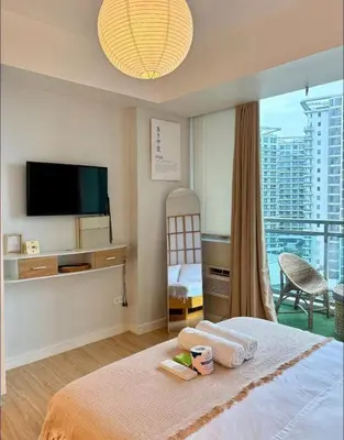 a bedroom with a bed with a television and a balcony at Boracay by SIA in Manila