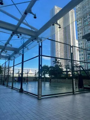 a view of a tennis court through a fence in a city at 2BR Condo - Makati CBD, Sunset Views, 20mins to NAIA in Manila