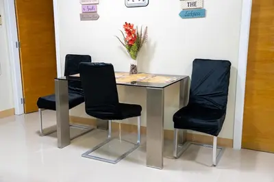 a table with three black chairs and a vase of flowers at Solemare Parksuites - Condo In Parañaque Near MOA ARENA, SMX CONVENTION CENTER AND DFA MAIN OFFICE in Manila