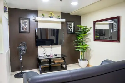 a living room with a black couch and a mirror at Solemare Parksuites - Condo In Parañaque Near MOA ARENA, SMX CONVENTION CENTER AND DFA MAIN OFFICE in Manila