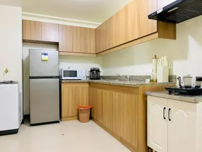 a kitchen with a white refrigerator and wooden cabinets at Vtan Condo FAIRLANE PASIG in Manila