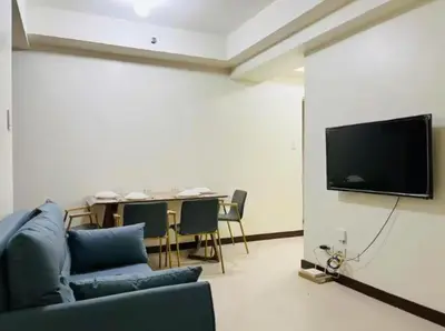 a living room with a couch and a tv on a wall at Vtan Condo FAIRLANE PASIG in Manila