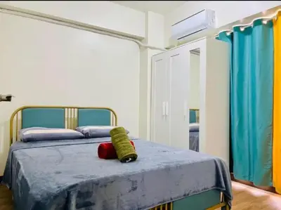 a bedroom with a bed with a blue comforter at Vtan Condo FAIRLANE PASIG in Manila