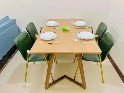a wooden table with green chairs and plates and napkins at Vtan Condo FAIRLANE PASIG in Manila