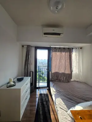 a bedroom with a bed and a dresser and a window at The Air Residences Makati in Manila