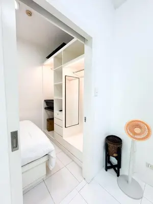 a white bedroom with a mirror and a chair at Vanity Calm Bedroom in Ortigas Center in Manila