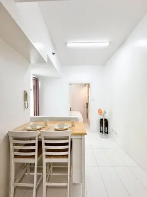 a white kitchen with a wooden table and chairs at Vanity Calm Bedroom in Ortigas Center in Manila