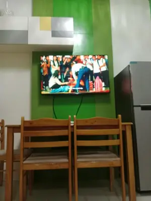 two wooden chairs and a tv on a green wall at Sea residences Christine prime in Manila