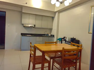 a kitchen with a wooden table and chairs at Apartment in Rhapsody 2BR in Manila