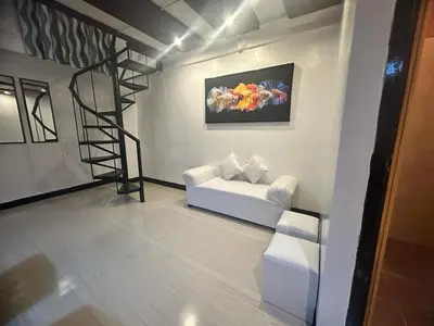 a living room with a white couch and a spiral staircase at Adorable - 2B, Stunning Lounge in Manila