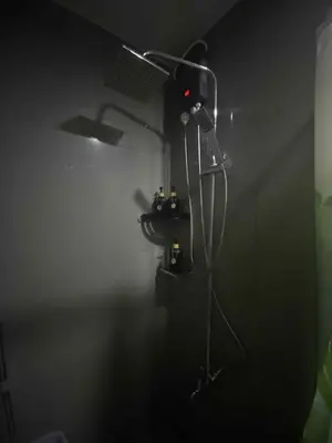 a bathroom with a shower in a dark room at SOLACE by Athena at Air Residences Makati in Manila