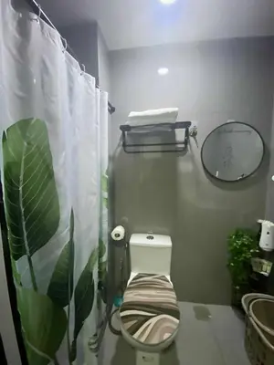 a bathroom with a toilet with a plant on the curtain at SOLACE by Athena at Air Residences Makati in Manila