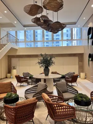 a lobby with chairs and a table in a building at Parkwest McKinley - 1 Bedroom Fully Furnished in Manila