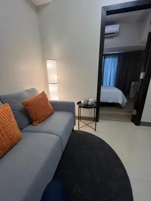 a living room with a couch and a mirror at Parkwest McKinley - 1 Bedroom Fully Furnished in Manila